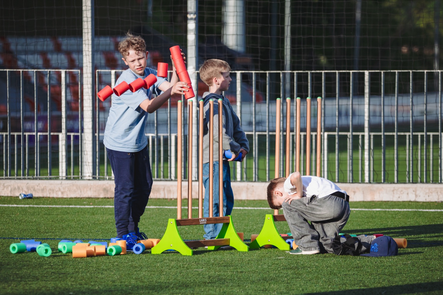 Boys stacking a tower of foam pool-noodle pieces