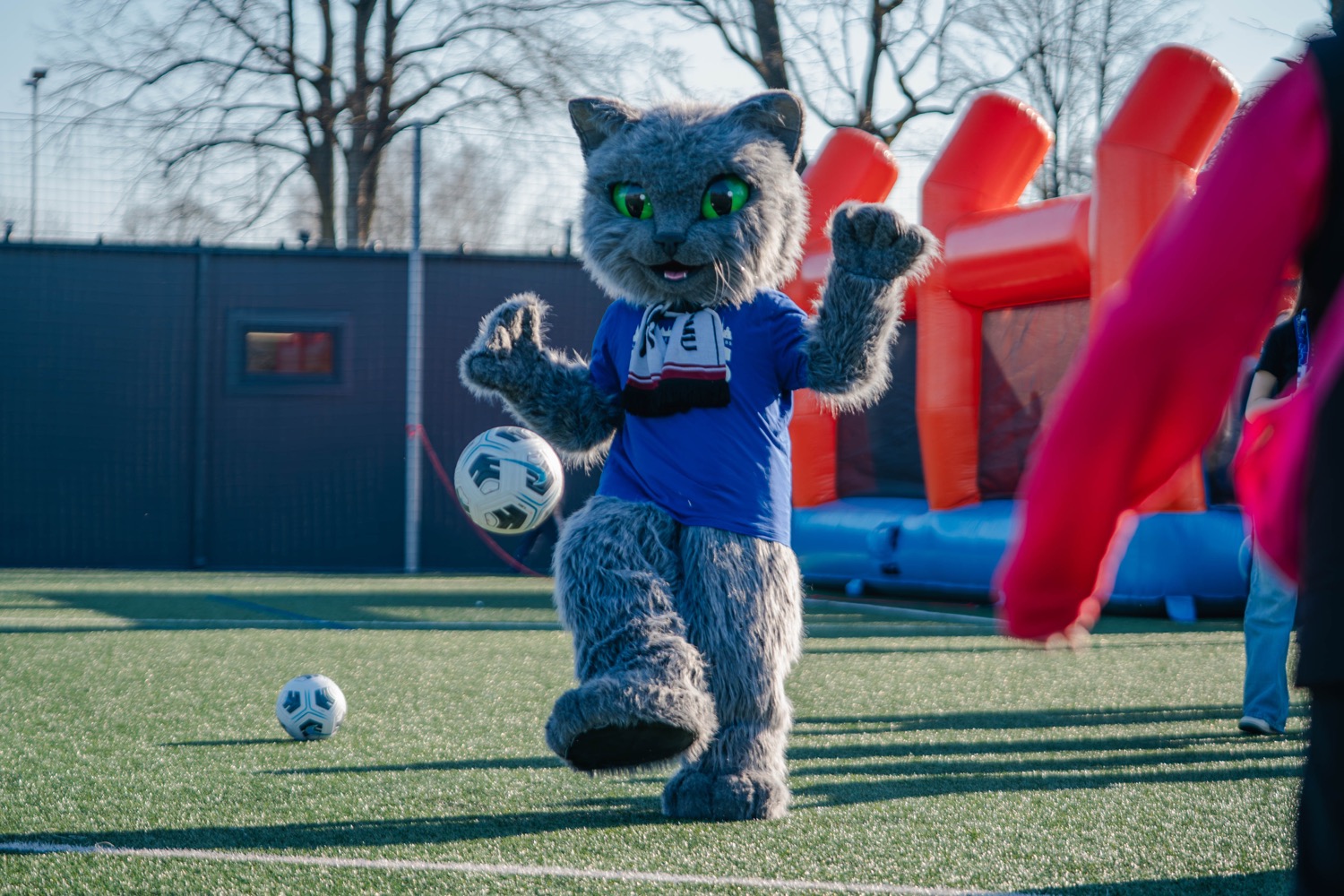 The club mascot playing football with children