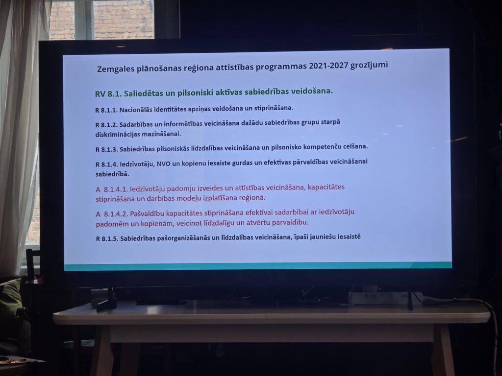 May be an image of television and text that says 'Zemgales plänošanas regiona attistibas programmas 2021-2027 grozijumi RV RV8.1 3.1. Saliedétas un pilsoniski aktivas sabiedribas veidošana. R8.1.1. Nacionalãs identitätes apzinas veidošana un stiprinäšana. R8.1.2. Sadarbibas un un informétibas veicinašana dažädu sabiedribas grupu starpă diskriminäcijas mazinašanai. R8.1.3. Sabiedribas pilsoniskas lidzdalibas veicinãšana un R8.1.4. ledzivotaju, NVO un kopienu iesaiste gurdas un efektivas pärvaldibas veicinăšanal sabiedribã. ilsonisko kompetenču celšana. A 8.1.4.1. ledzivotäju padomju izveides un attistibas veicinãšana, kapacitates stiprinăšana un darbibas modelu izplatišana regionã. 8.1.4.2. Pašvaldibu kapacitătes stiprinãšana efektivai sadarbibai padomém kopienam, veicinot lidzdaligu un atvértu pärvaldibu. iedzivotäju R8.1.5. Sabiedribas pašorganizešanăs un lidzdalibas veicinãšana, ipaši jauniešu iesaisté'